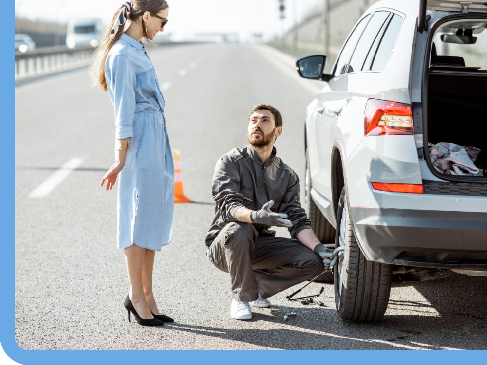 mechanic helping client change tire on roadside