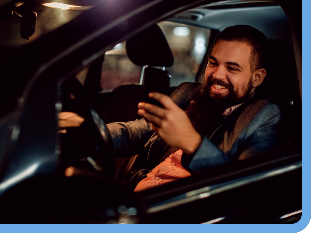 man in car at night smiling at phone